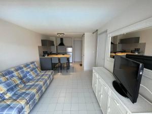 ein Wohnzimmer mit einem Sofa und einem Flachbild-TV in der Unterkunft Appartement Cap d'Agde, 3 pièces, 6 personnes - FR-1-723-54 in Cap d'Agde