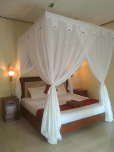 a bedroom with a canopy bed with white curtains at Pondok Aldi in Amed