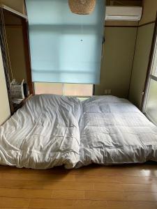 an unmade bed in a room with a wooden floor at 晋shin宇治浦田 in Uji