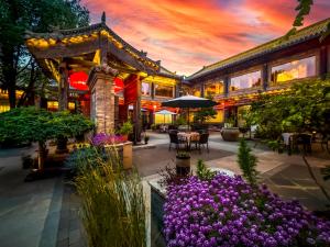 a building with a garden with purple flowers in front of it at Datong Yunzhong Traditional Courtyard in Datong