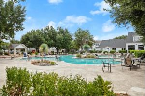 a swimming pool at a resort with chairs and tables at Comfy& stylish ~2bed~2Bath ~8 minute to Downtown in Austin