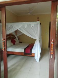 a bed with a canopy in a room at Pondok Aldi Hostel in Amed