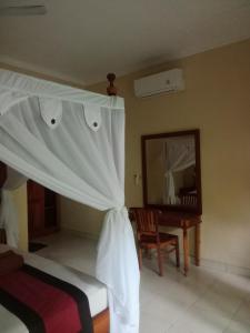a bedroom with a bed and a mirror and a chair at Pondok Aldi Hostel in Amed