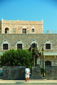 um homem parado em frente a uma estátua em frente a um edifício em Areos Polis Boutique Hotel em Areopoli