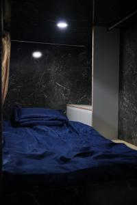 1 dormitorio con 1 cama azul y pared de piedra en D-Dorm Home, en Ho Chi Minh