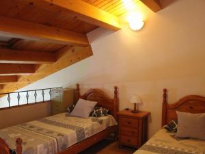 2 camas num quarto com tectos em madeira em Belvilla by OYO Mas Set Rengs 2 em Guardiola