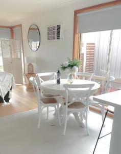 a white dining room with a white table and chairs at Coastal Springs - PET FRIENDLY & 200m To Beach! in Clifton Springs
