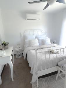 a white bed with white pillows and a ceiling fan at Coastal Springs - PET FRIENDLY & 200m To Beach! in Clifton Springs