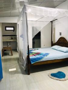 a bed with a canopy in a room at Nethmi Homestay & Restaurant in Tangalle