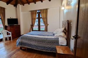 1 dormitorio con 1 cama, TV y ventana en QHAPAQ WASI, en Cusco