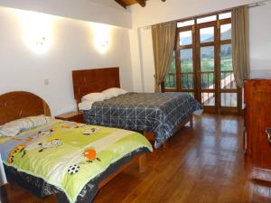 1 dormitorio con 2 camas y ventana con vistas en QHAPAQ WASI, en Cusco