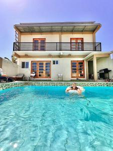 a woman swimming in a swimming pool in front of a house at Bahai ni Jhane in Calatagan