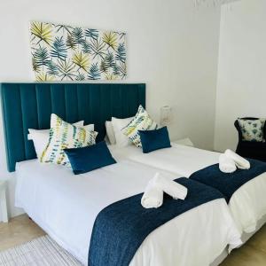2 Betten mit blauen und weißen Kissen im Schlafzimmer in der Unterkunft Tropicana Guesthouse in Ponta do Ouro