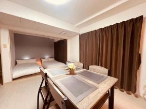 a room with a table and a bed in the background at HS平岸 HSHiraghishi in Minami-jūichijō