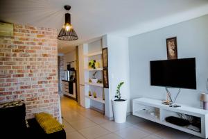 a living room with a tv and a brick wall at One bedroom flat in Wild Olive apartments in Windhoek