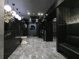 a lobby with a hallway with black walls and a marble floor at HOTEL NOIR Kagoshima Chuo Station in Kagoshima