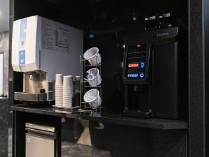 - un comptoir noir avec une machine à café dans l'établissement HOTEL NOIR Kagoshima Chuo Station, à Kagoshima