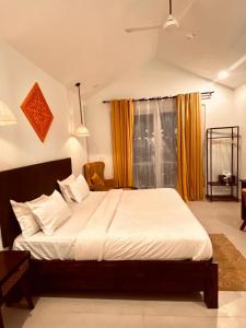 1 dormitorio con 1 cama blanca grande con cortinas amarillas en Tvessa - A Boutique Hotel, en Mandrem