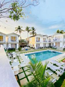 a resort with a pool and chairs and palm trees at Tvessa - A Boutique Hotel in Mandrem