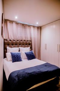a bedroom with a large bed with blue and white pillows at One bedroom flat in Wild Olive apartments in Windhoek