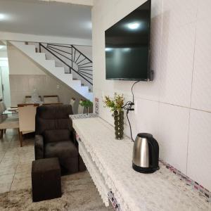 a living room with a table with a television on the wall at Hostel Inn Gileade in Belém