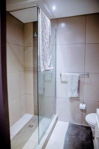 a shower with a glass door in a bathroom at One bedroom flat in Wild Olive apartments in Windhoek