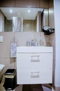 a white bathroom with a sink and a mirror at One bedroom flat in Wild Olive apartments in Windhoek