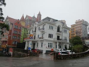 a white building with cars parked in front of it at Tam Đảo Hotel in Tam Ðảo