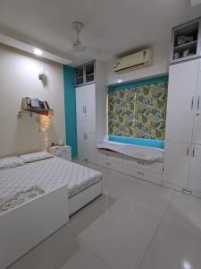 a white bedroom with a bed and a window at Soul House_4.5 BHK Apartment in Ahmedabad