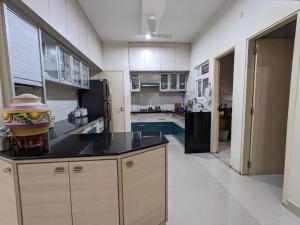 a large kitchen with a black counter top and cabinets at Soul House_4.5 BHK Apartment in Ahmedabad
