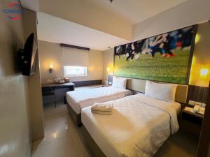 um quarto de hotel com duas camas e um quadro na parede em Cordela Kartika Dewi Yogyakarta em Yogyakarta