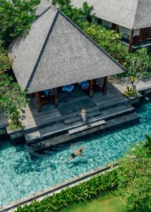 an overhead view of two people in the water at a resort at La Reserve 1785 Canggu Beach in Canggu