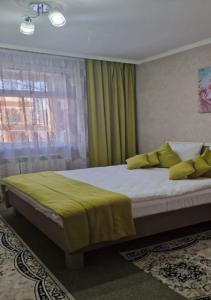 a bedroom with a bed with yellow pillows and a window at Hotel Miss Mari in Karagandy