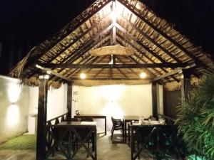 a restaurant with tables and chairs under a wooden roof at elephant eye safari house in Udawalawe