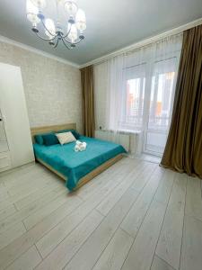 1 dormitorio con cama azul y ventana grande en Сдам однокомнатную квартиру по Туран 55/6, en Taldykolʼ