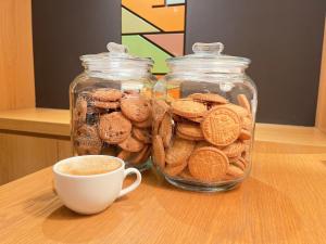 a cup of coffee next to glass jars of cookies at Henn na Hotel Tokyo Nishikasai in Tokyo