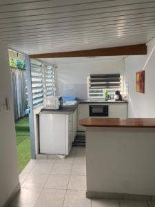 eine Küche mit weißen Schränken und einer Arbeitsplatte in der Unterkunft T2 calme à Remire-Montjoly in Rémire-Camp
