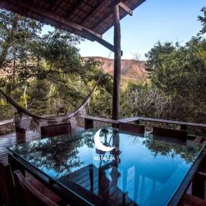 a glass table on a deck with a view of the mountains at Casa da Mata - Sao Jorge GO in Sao Jorge