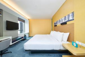 um quarto de hotel com uma cama grande e uma secretária em Aloft Zhengzhou Shangjie em Zhengzhou