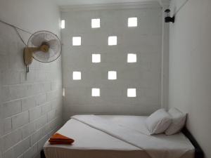 Kep Family House & Restaurant في Phumĭ Ŏng Char: غرفة بيضاء مع سرير ومروحة
