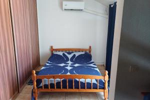 a small bed in a room with a blue and white comforter at Fare Gauguin in Papeete