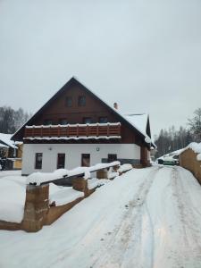 a barn covered in snow on a dirt road at Ubytování Niki in Rokytnice nad Jizerou