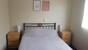 a bedroom with a bed with two dressers and two lamps at Billungar Unit 2 at Hat Head - 1 Creek Street in Hat Head
