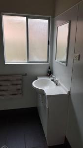 a white bathroom with a sink and two windows at Billungar Unit 2 at Hat Head - 21 Creek Street in Hat Head