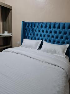 a large bed with a blue headboard and white pillows at La Ribera Cosy Homes in Bomet