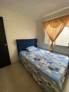 Schlafzimmer mit einem Bett mit blauem Kopfteil und einem Fenster in der Unterkunft Encantadora villa en una cdla privada in Candelaria