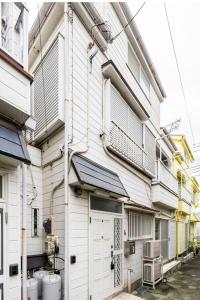 un edificio blanco con una puerta y ventanas blancas en アンドステイ柴又5丁目B en Tokio