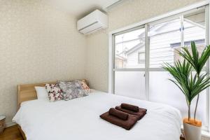 1 dormitorio con cama blanca y ventana en アンドステイ柴又5丁目B, en Tokio