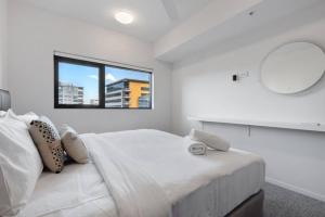 una camera bianca con un grande letto e uno specchio di South Brisbane One Bedroom Apartment a Brisbane