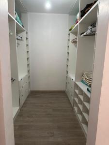 einen begehbaren Kleiderschrank mit weißen Wänden und Holzböden in der Unterkunft Casa cómoda, grande y agradable. in Arica